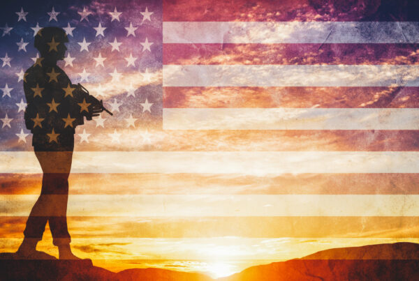 Armed soldier with rifle standing and looking on horizon. USA flag. Silhouette at sunset. War, army, military, guard.